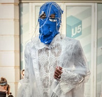 Artist pictured wearing original design lace and chiffon jumpsuit with a blue balaclava by Predrag Petrovic 
