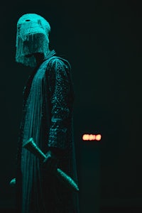 a person in a costume holding a knife in the dark